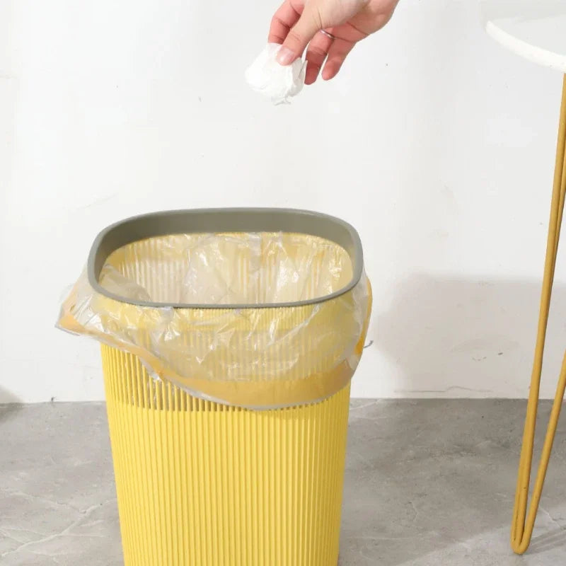 Une personne jette un papier dans une poubelle nordique jaune